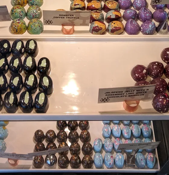 Deep navy and maroon Jalapeno Jelly bonbons behind glass.